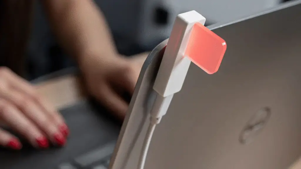 Best Smart Home Devices for Remote Workers in the US (2025 Guide) 8 A woman typing on a MacBook and Luxafor Flag is attched