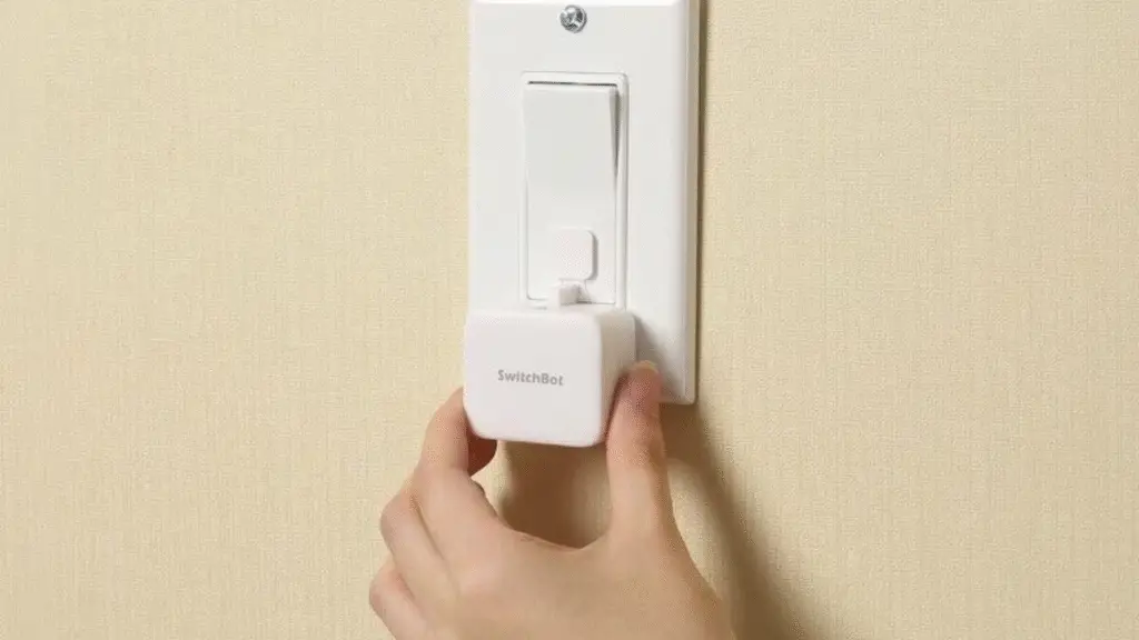A hand of female holding a Switchbot on a switch to automate the switch 